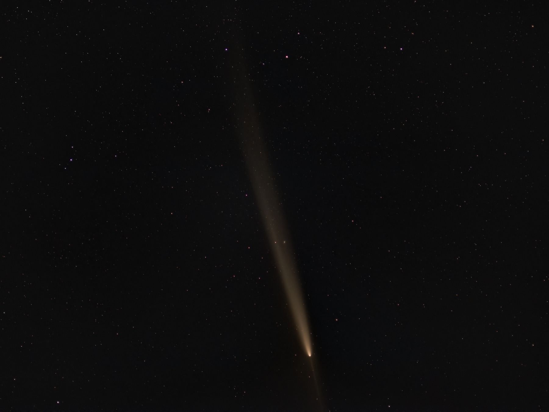 Comet C/2023 A3 with a long tail against a starfield