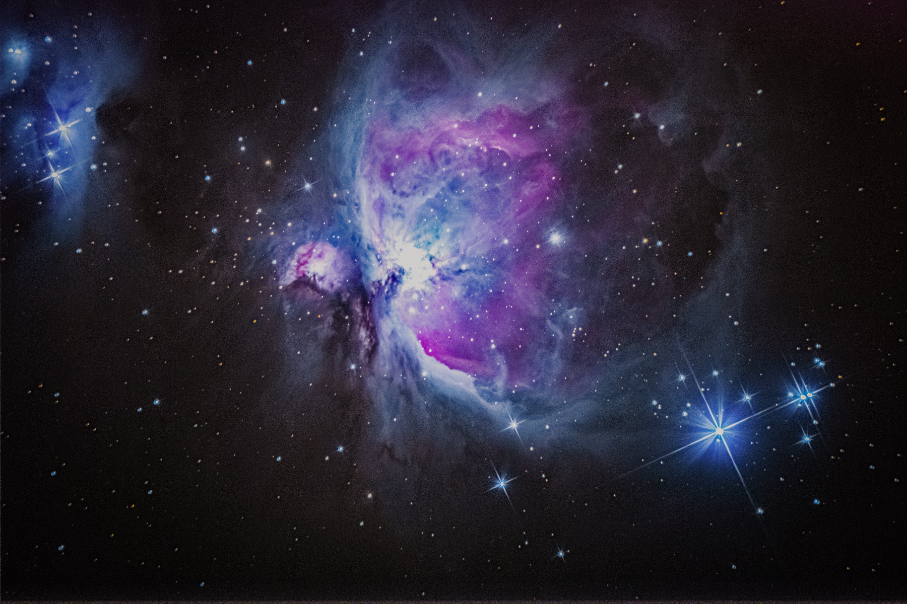The Orion Nebula, glowing pink and blue clouds of gas among stars
